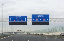 Snelweg met boven de weg blauwe verkeersborden waarom de richting staat aangegeven: rechtdoor is op de A1 blijven, rechtsaf is naar de A9 Haarlem/Schiphol/Amsterdam-Zuidoost