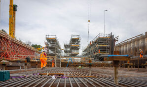 Een foto van de bouwplaats met veel stijgers en betonconstructies.